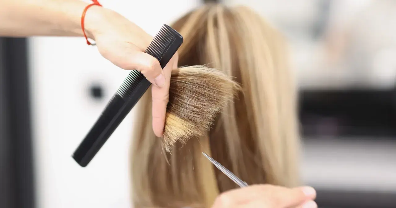 Fryzjerka tworzy modną fryzurę na szwedkę, precyzyjnie modelując blond włosy nożyczkami i grzebieniem.