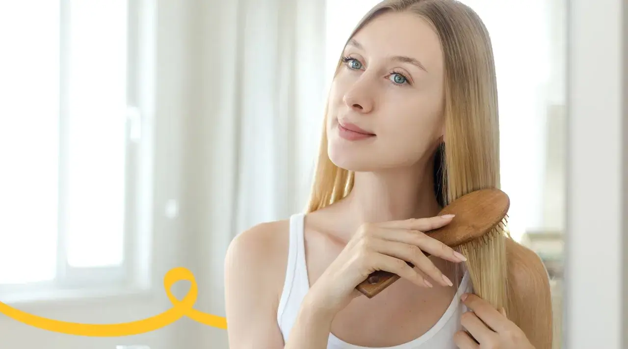 Kobieta szczotkuje włosy, przygotowując je na domowy peeling do skóry głowy.