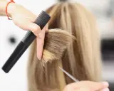 Fryzjerka tworzy modną fryzurę na szwedkę, precyzyjnie modelując blond włosy nożyczkami i grzebieniem.