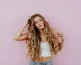 Kobieta z falowanymi blond włosami, które wyglądają na zdrowe i lśniące, jakby użyto krzemu na włosy.