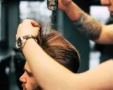 Stylista pokazuje, jak używać pudru do włosów, aplikując go na męską fryzurę dla objętości i tekstury.