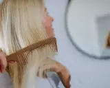 Kobieta czesze blond włosy, szukając rozwiązań co na wypadanie włosów po ciąży.