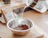 Gorąca woda zalewa kawę w misce, przygotowując naturalny sposób na farbowanie włosów kawą.