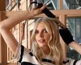 Blondynka tworzy łamane loki prostownicą, pokazując jak zrobić fryzurę krok po kroku.
