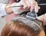 Profesjonalne farbowanie odrostów. Rękawiczki i pędzel z farbą precyzyjnie aplikują produkt na linię włosów.