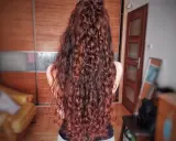 Długie, falowane włosy w odcieniu rudego brązu, ułożone w luźny kok. Efekt pięknej, naturalnej wavy hair routine.