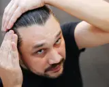 Mężczyzna sprawdza swoje włosy, martwiąc się o kreatynę a wypadanie włosów.