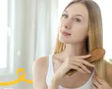 Kobieta szczotkuje włosy, przygotowując je na domowy peeling do skóry głowy.