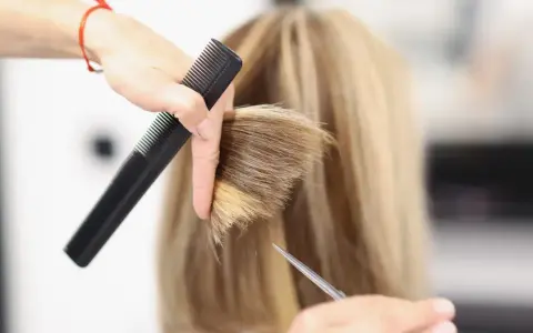 Fryzjerka tworzy modną fryzurę na szwedkę, precyzyjnie modelując blond włosy nożyczkami i grzebieniem.