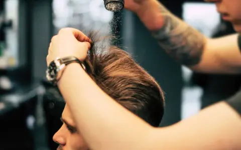 Stylista pokazuje, jak używać pudru do włosów, aplikując go na męską fryzurę dla objętości i tekstury.