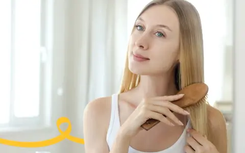 Kobieta szczotkuje włosy, przygotowując je na domowy peeling do skóry głowy.