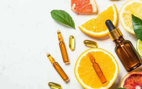 Naturalne **witaminy w kosmetyce**: ampułki, kapsułki i cytrusy symbolizujące pielęgnację.