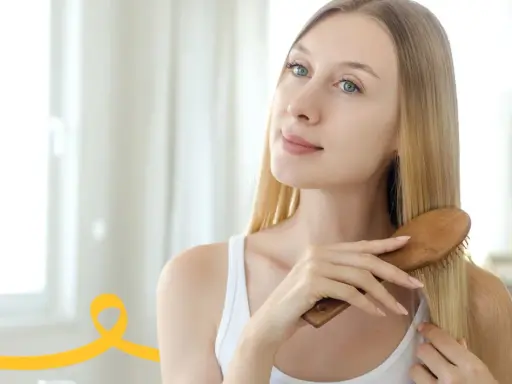 Kobieta szczotkuje włosy, przygotowując je na domowy peeling do skóry głowy.